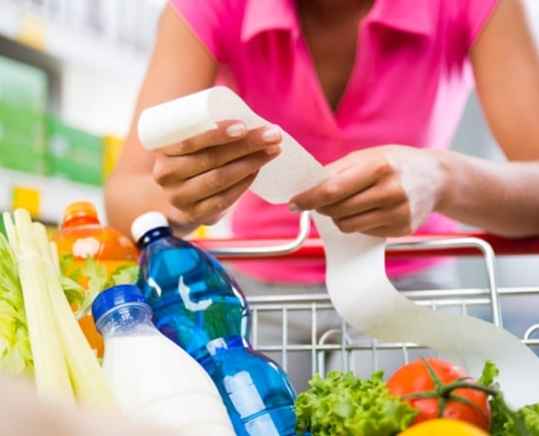 A woman checks her grocery receipt to see how much money she spent