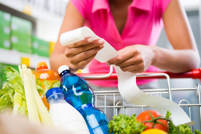 A woman checks her grocery receipt to see how much money she spent