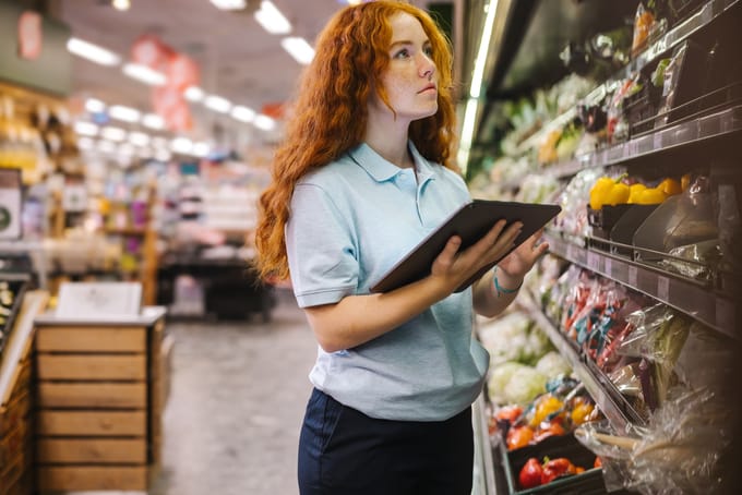 A produce department employee visually inspects fresh produce