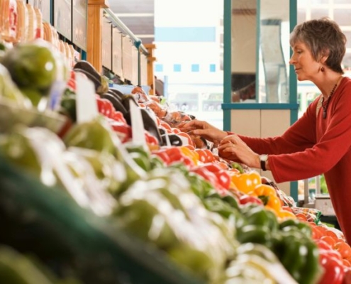 An older woman shops for peppers in her local grocery store