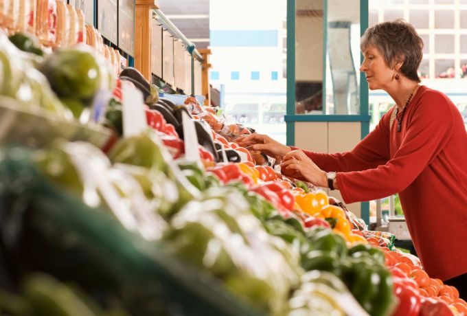An older woman shops for peppers in her local grocery store