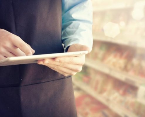 A grocery store employee looks up information on his tablet