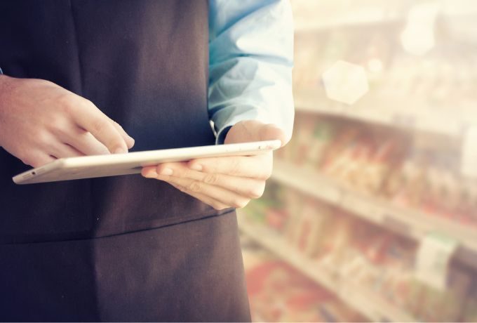 A grocery store employee looks up information on his tablet