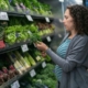 A woman inspects fresh herbs in a grocery store produce department