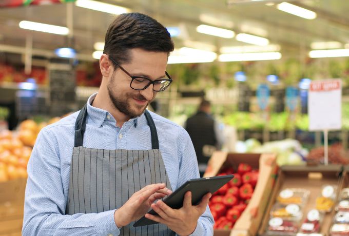 A grocery store employee using a tablet