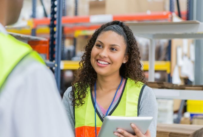 A woman working in a produce distribution center uses a tablet to perform a quality inspection